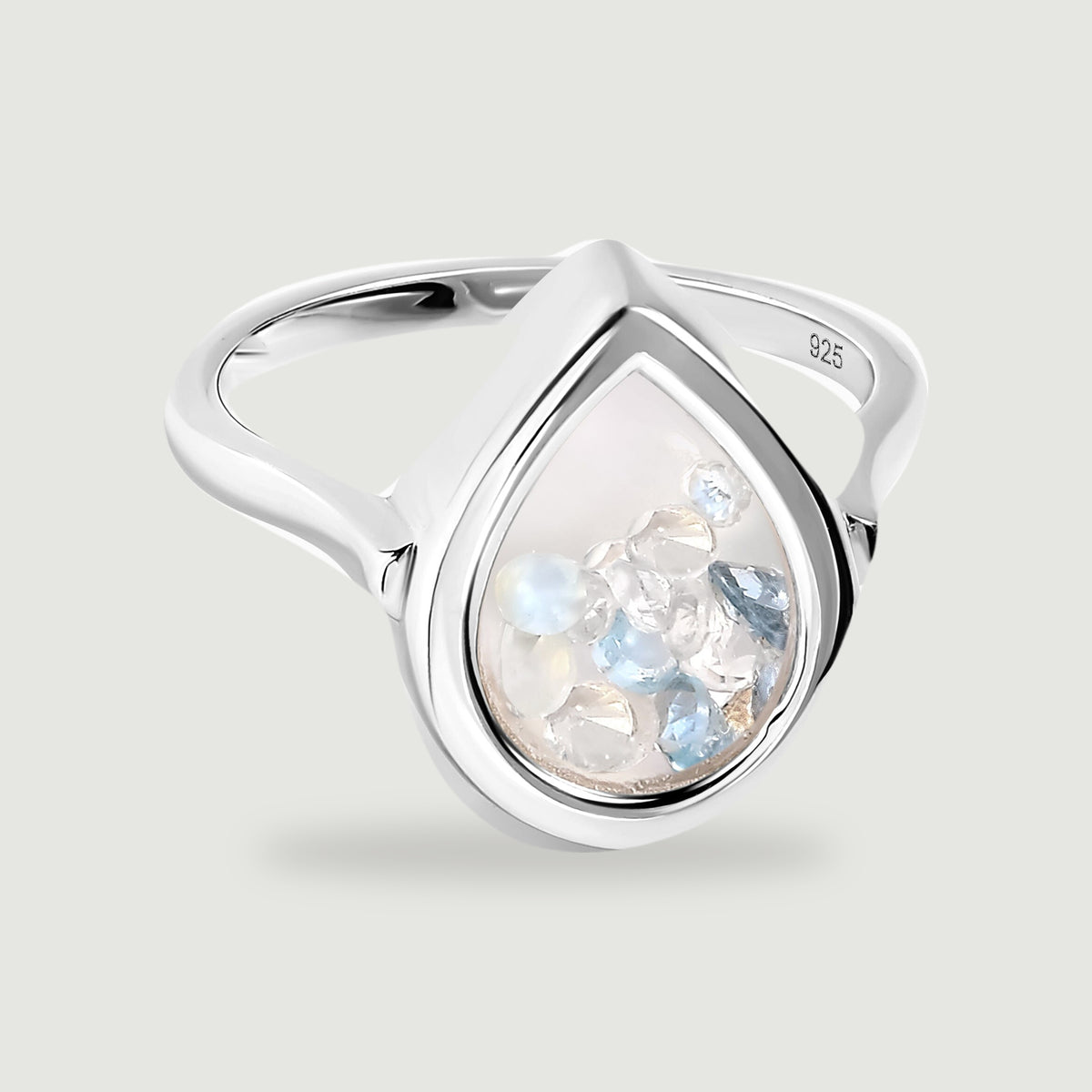 A polished silver ring has a pear-shaped glass chamber containing pale blue, clear and milky white gems.