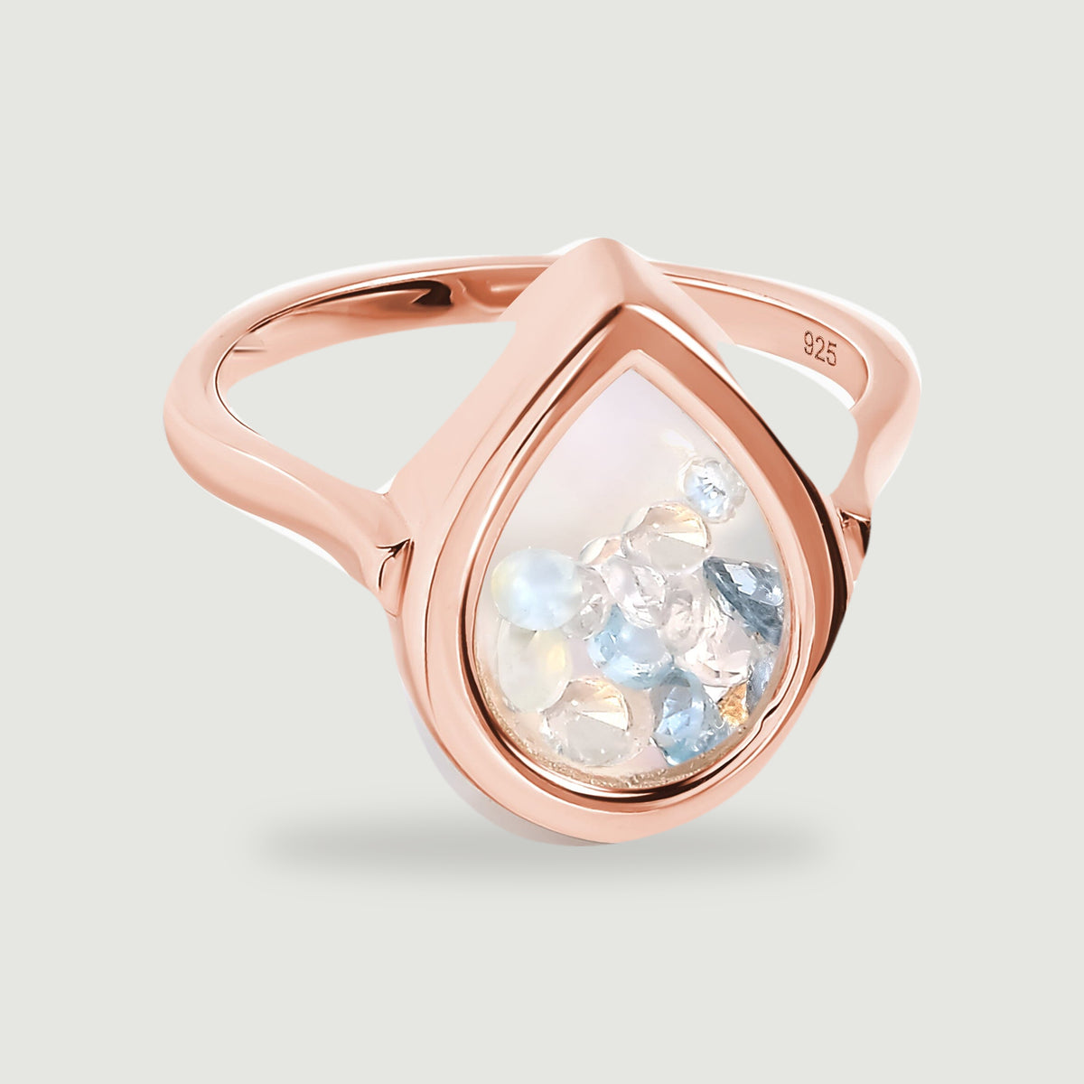 A rose gold ring surrounds loose blue and translucent gems with a smooth pear-shaped rim.