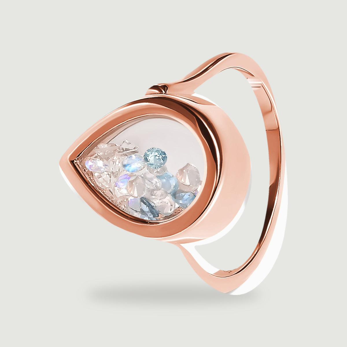 A tilted rose gold ring shows its smooth band and the raised edge around a pear-shaped glass window.