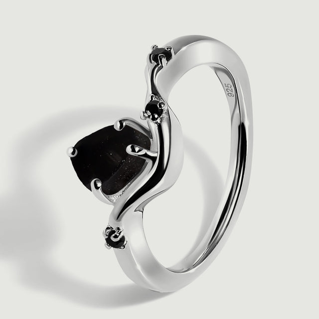 An angled view shows the silver band, raised black center stone and small black accent stones.