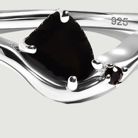 A close view shows the dark center stone held by bright silver prongs above a curved band.