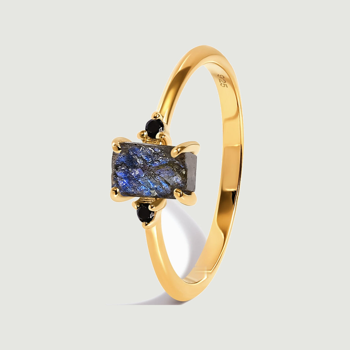 An angled yellow gold vermeil ring reveals four prongs around the blue-grey stone and a smooth curved band.