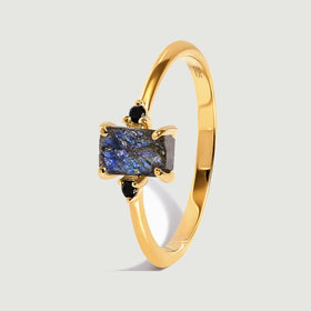 An angled yellow gold vermeil ring reveals four prongs around the blue-grey stone and a smooth curved band.