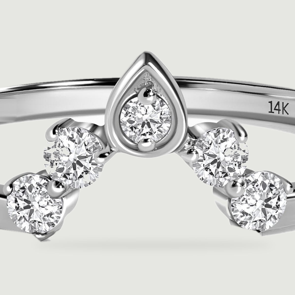 A close view shows the faceted round diamonds and pointed central setting of the white gold ring.