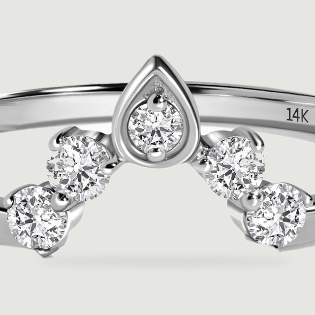 A close view shows the faceted round diamonds and pointed central setting of the white gold ring.