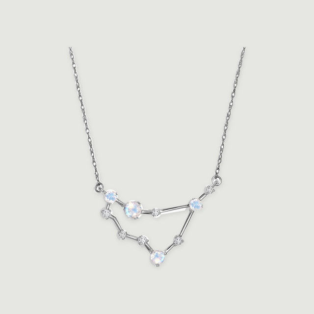 A white gold chain holds an angular pendant with four iridescent round moonstones and small clear stones.