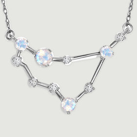 The complete angular pendant rests on a pale gray surface with its two chain attachment loops visible.