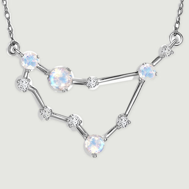 The complete angular pendant rests on a pale gray surface with its two chain attachment loops visible.