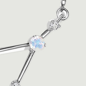 The right chain loop connects to a clear stone and a round moonstone through polished white gold links.