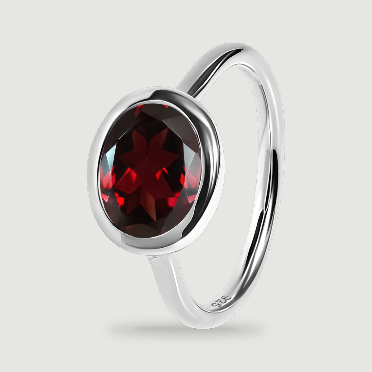 The garnet facets and silver bezel are visible beside the curved band in an upright ring view.