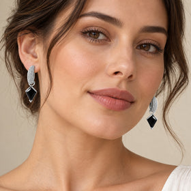 Pair of kite-cut hoops with black obsidian drops, shown on a model in soft daylight