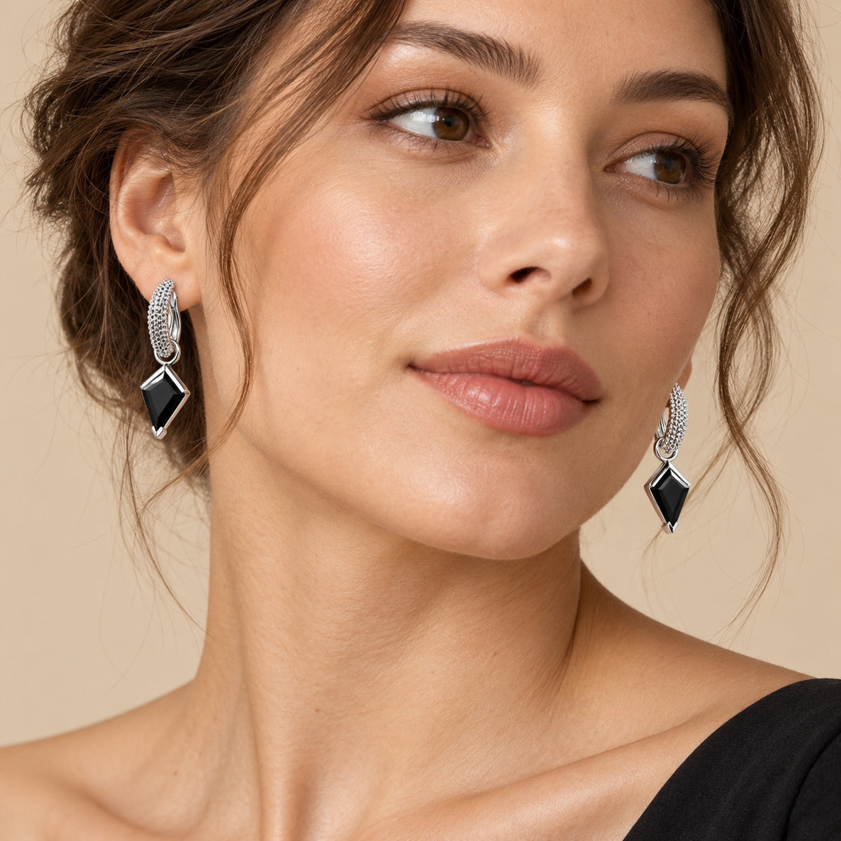 Model wearing kite-cut black obsidian hoop earrings, three-quarter view