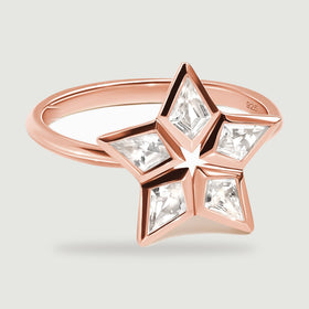 Five clear kite-shaped stones frame an open star on a rose gold ring shown at a low angle.