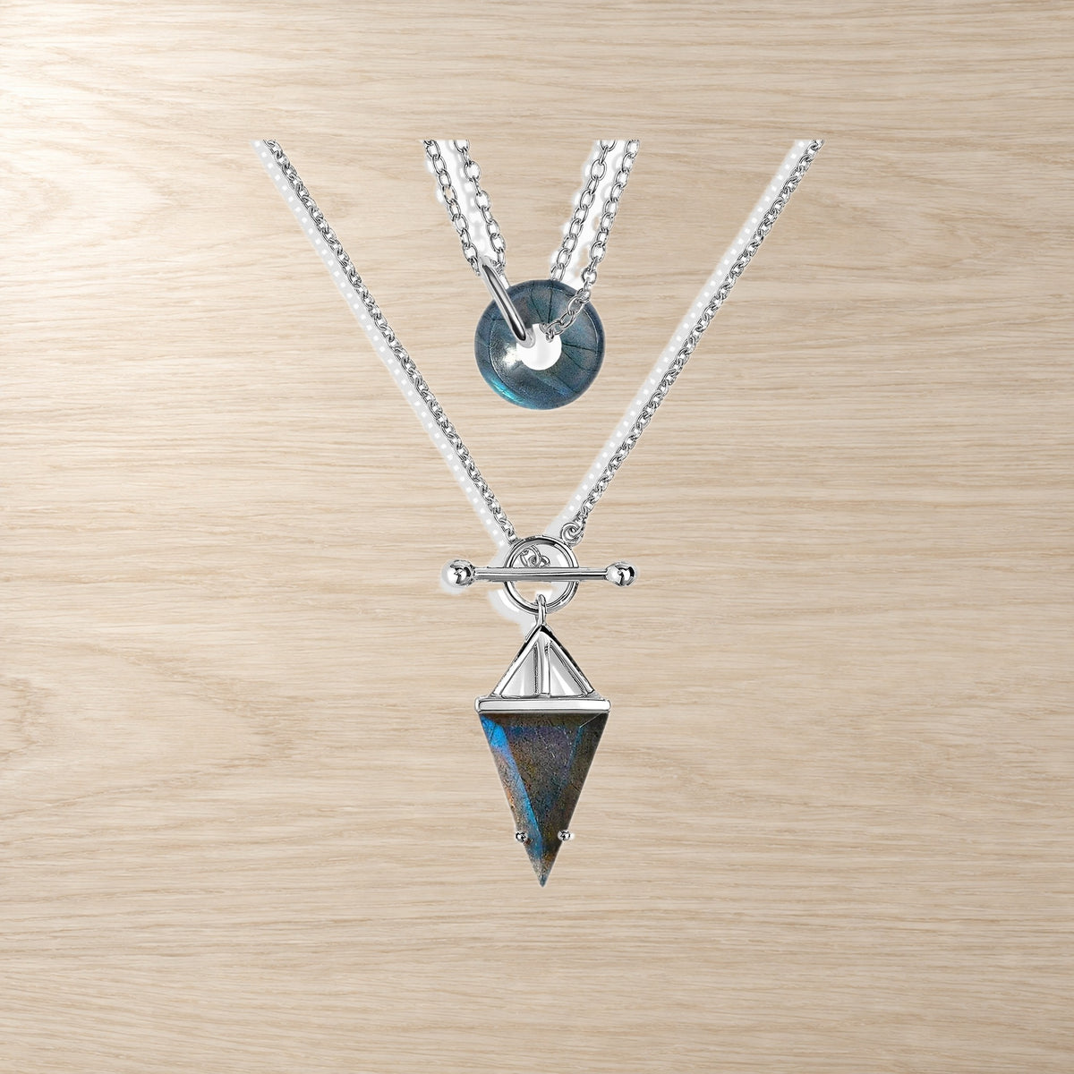 Two labradorite necklaces on a wooden surface, one with a donut and one with a triangle pendant