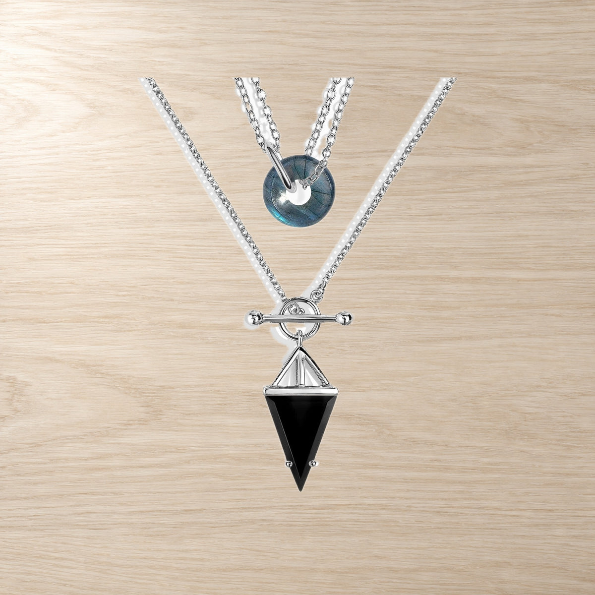 Two necklaces on a wooden surface, one with a labradorite donut and one with a black obsidian pendant