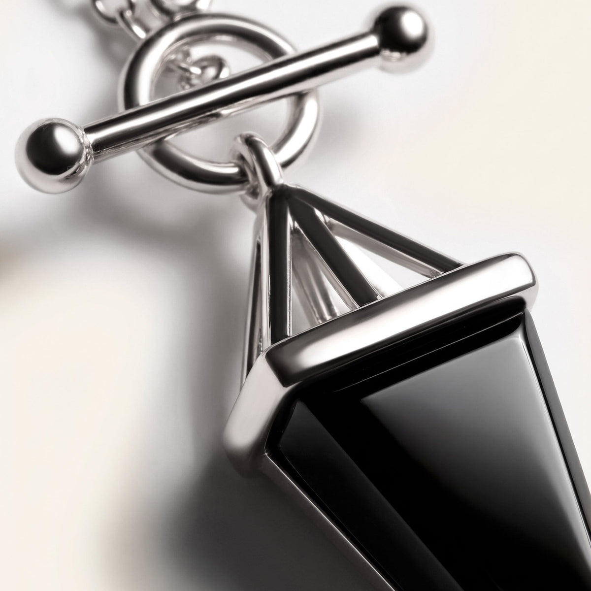 Black obsidian pendant with a silver bar, close-up on a black background
