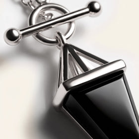 Black obsidian pendant with a silver bar, close-up on a black background