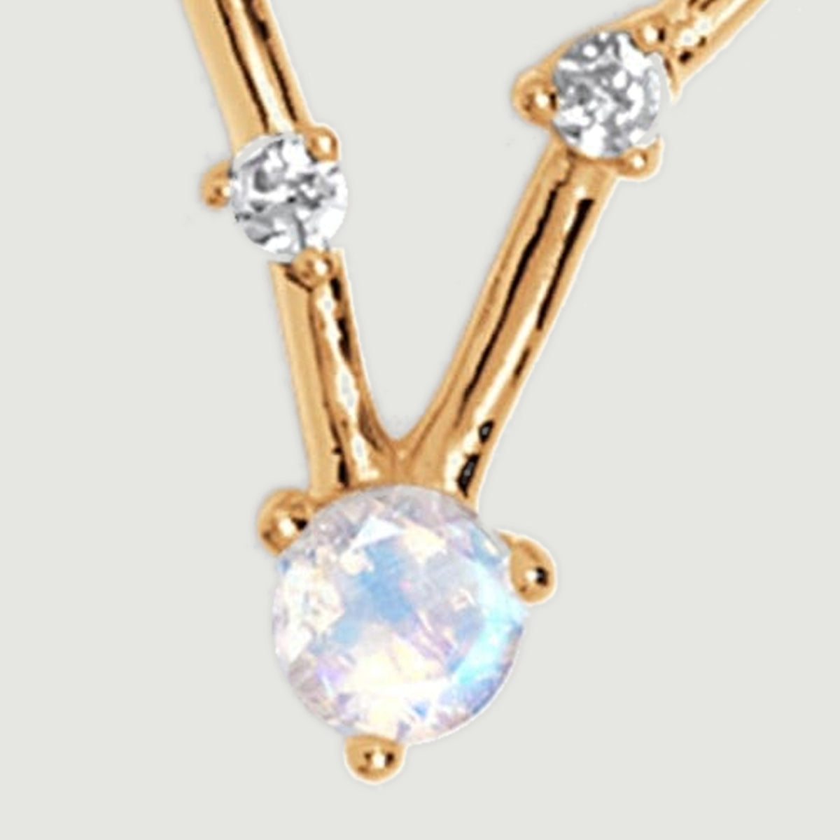 The lower moonstone and two clear stones are joined by slender polished gold bars.