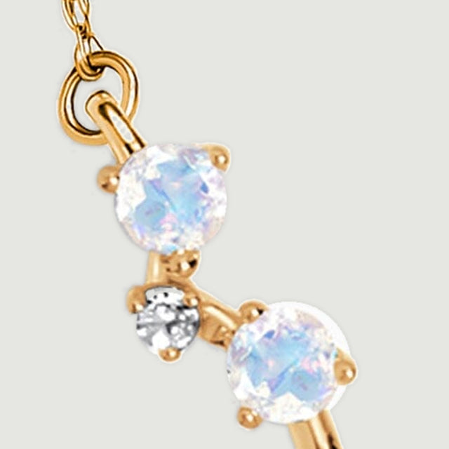Two pale moonstones and a small clear stone meet the fine gold chain on the left side of the pendant.