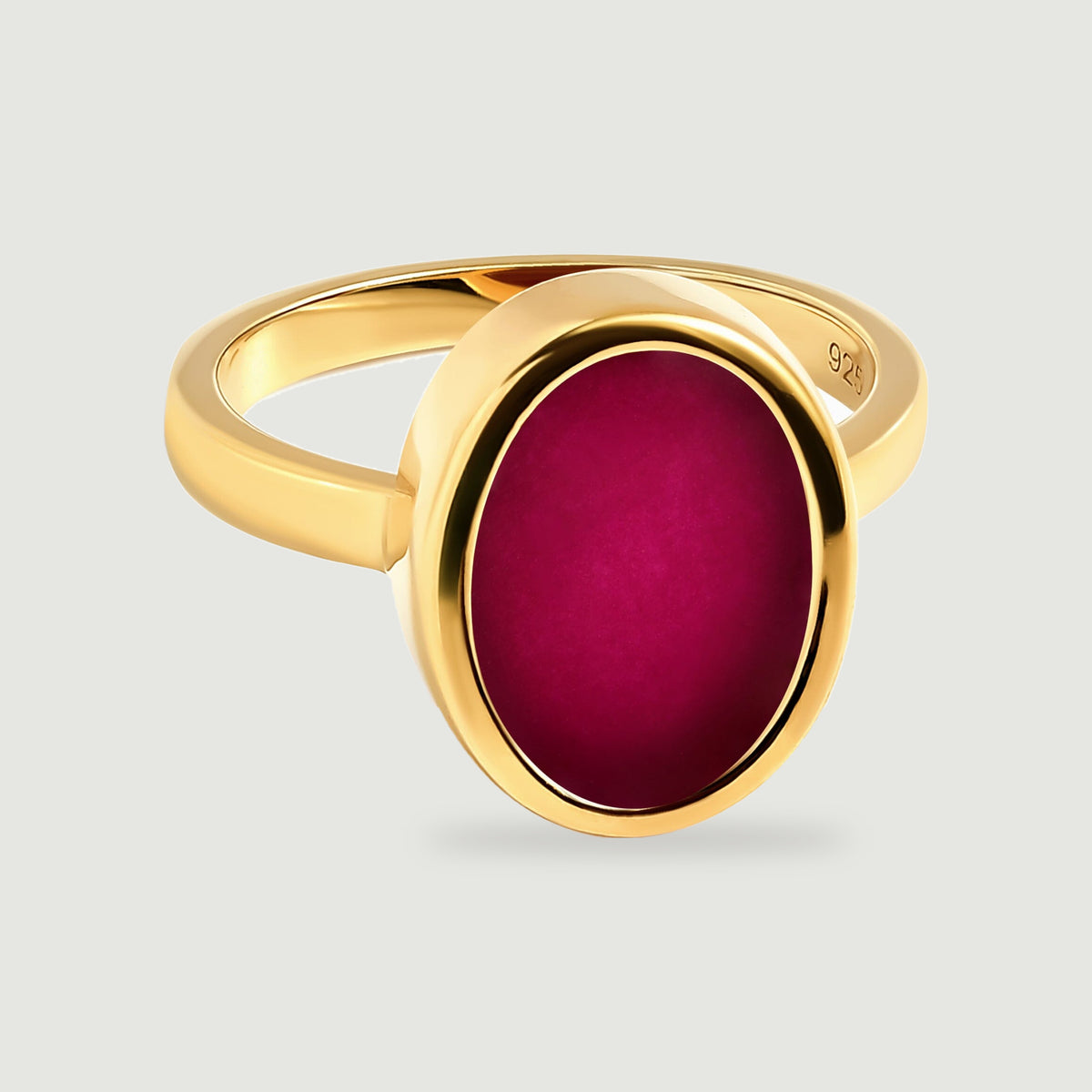 A yellow gold ring displays an oval pink stone surrounded by a smooth polished bezel.