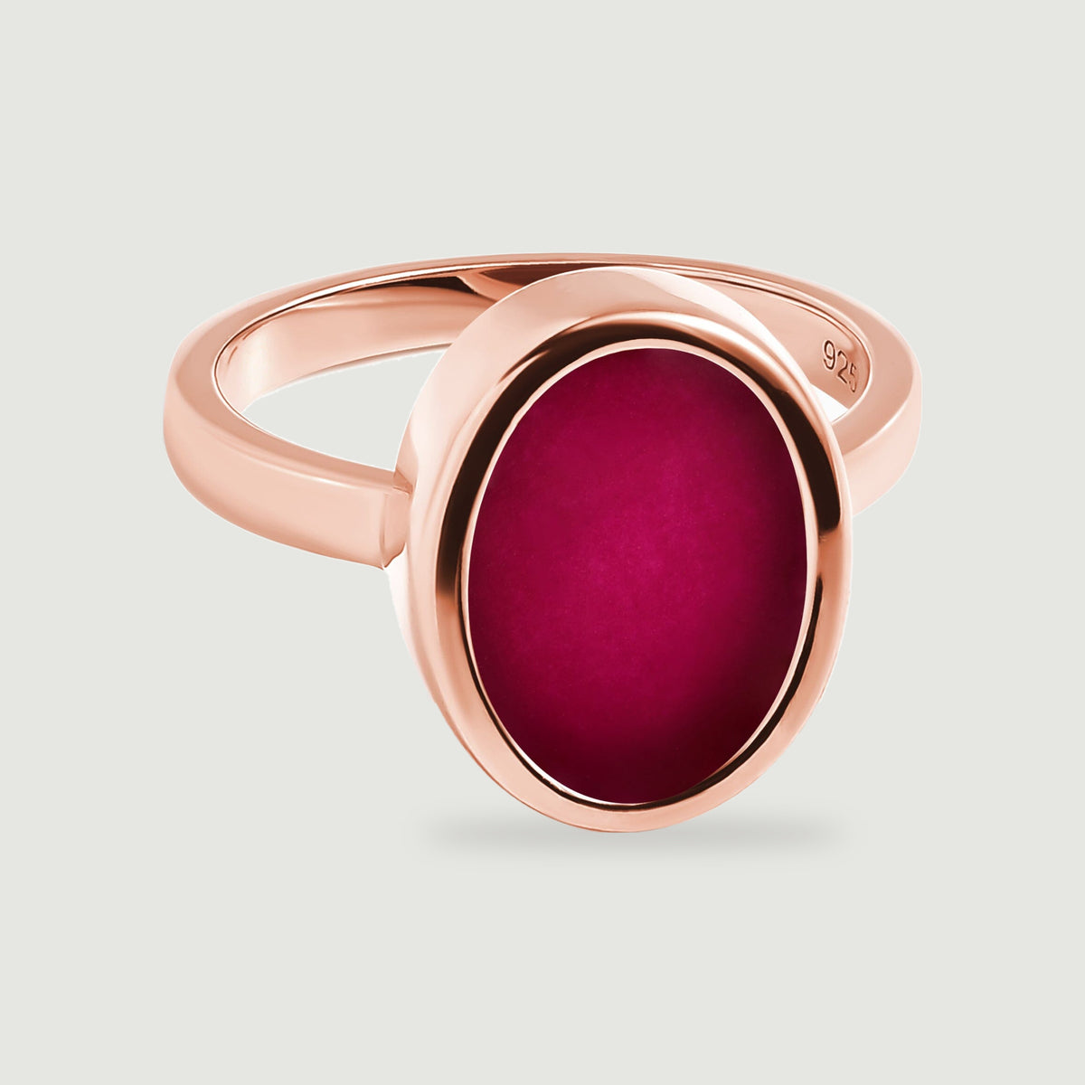 A rose gold ring with a flat oval pink stone is centered against a pale gray background.