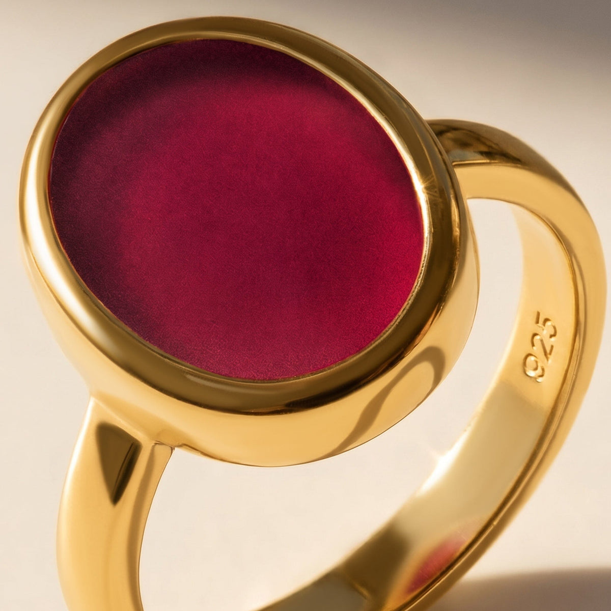 The oval pink stone, rounded yellow gold bezel, and inner band are shown in close detail.