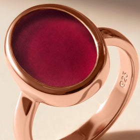 A close-up reveals the pink stone surface, rose gold rim, and the curved polished band.