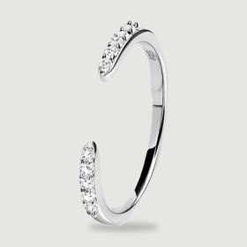 An upright silver ring reveals its slim curved profile and clear stones beside the open gap.