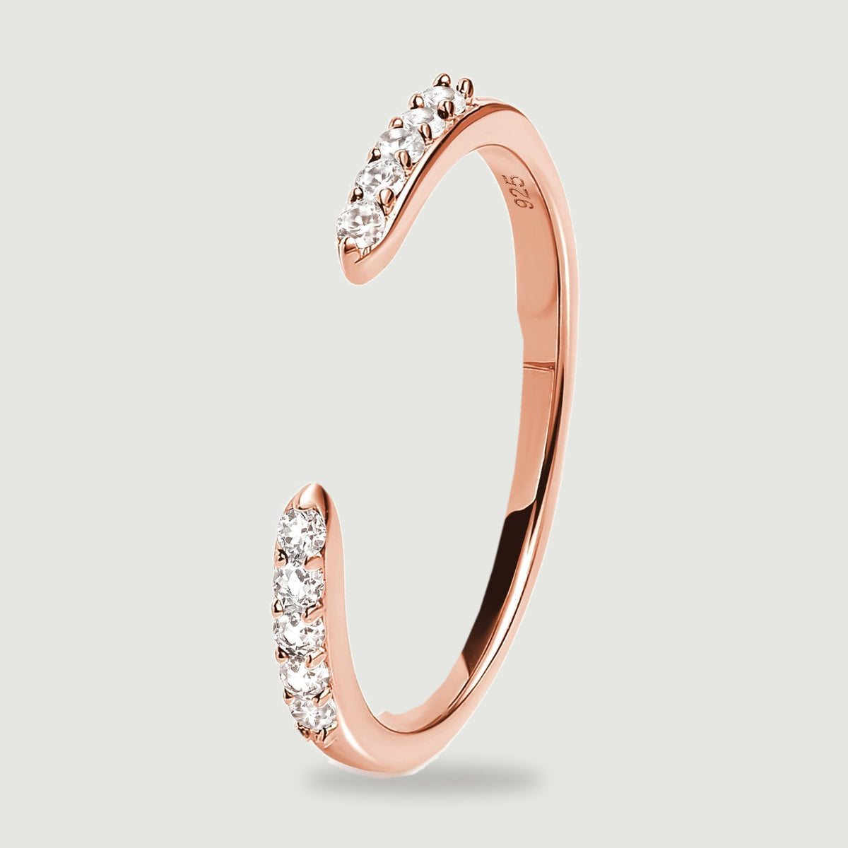 The rose gold ring stands at an angle with two stone set tips and a smooth curved shank.