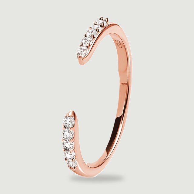 The rose gold ring stands at an angle with two stone set tips and a smooth curved shank.