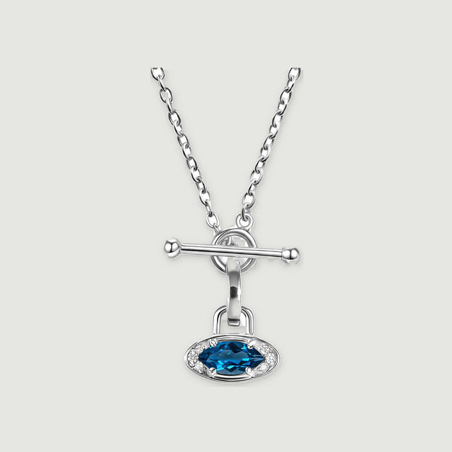 A silver necklace with an oval blue gemstone, clear accent stones and a bar clasp is centered on a light gray background.