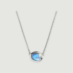 A polished silver-colored bezel surrounds a faceted moonstone at the center of a delicate necklace.