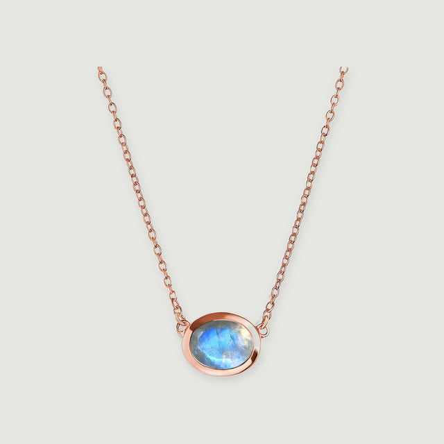A rose gold necklace frames a translucent moonstone with a bright blue reflection.
