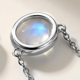 An angled view shows the depth of the silver-colored bezel and the chain loops beside the moonstone.