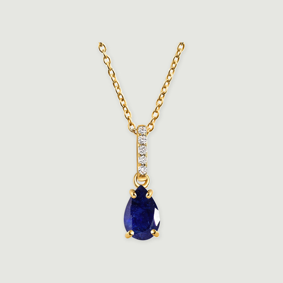 A yellow gold necklace has a pear-shaped blue sapphire below a vertical row of five clear stones.