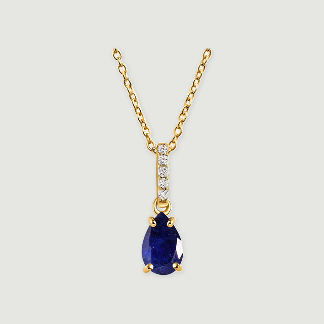 A yellow gold necklace has a pear-shaped blue sapphire below a vertical row of five clear stones.
