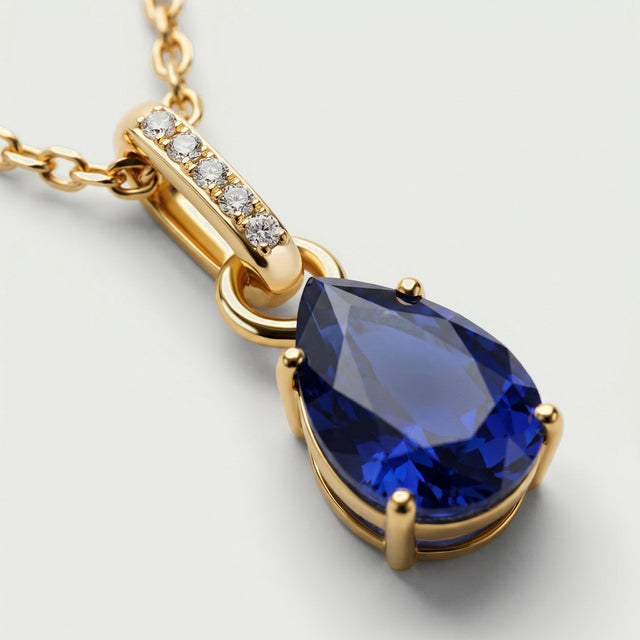 A close view shows the blue sapphire facets, gold prongs, and five clear stones along the bail.