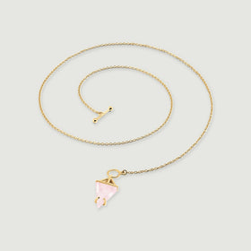 A yellow gold necklace is laid in a curved coil with a pink triangular stone and a separate toggle bar.