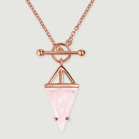 Warm rose gold prongs hold the tapered pink stone below an open geometric frame and circular fastening.