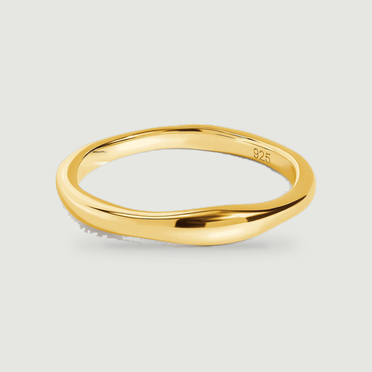 A yellow gold ring shows its smooth curved band and open center against light gray.