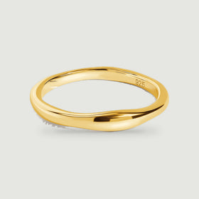 A yellow gold ring shows its smooth curved band and open center against light gray.