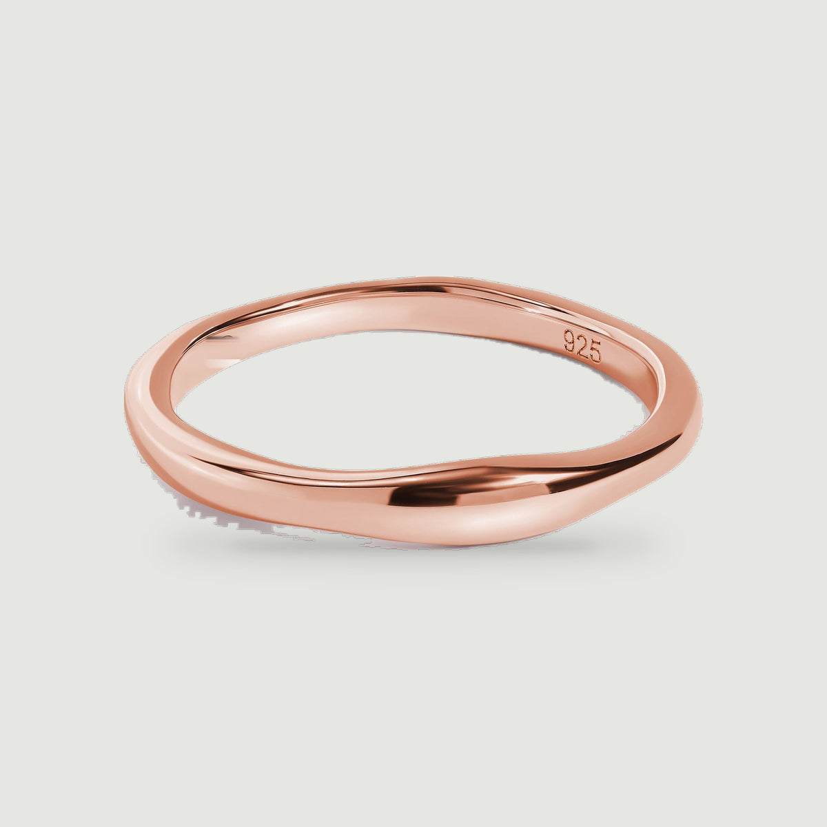 A rose gold ring displays its rounded profile and reflective finish on a gray background.
