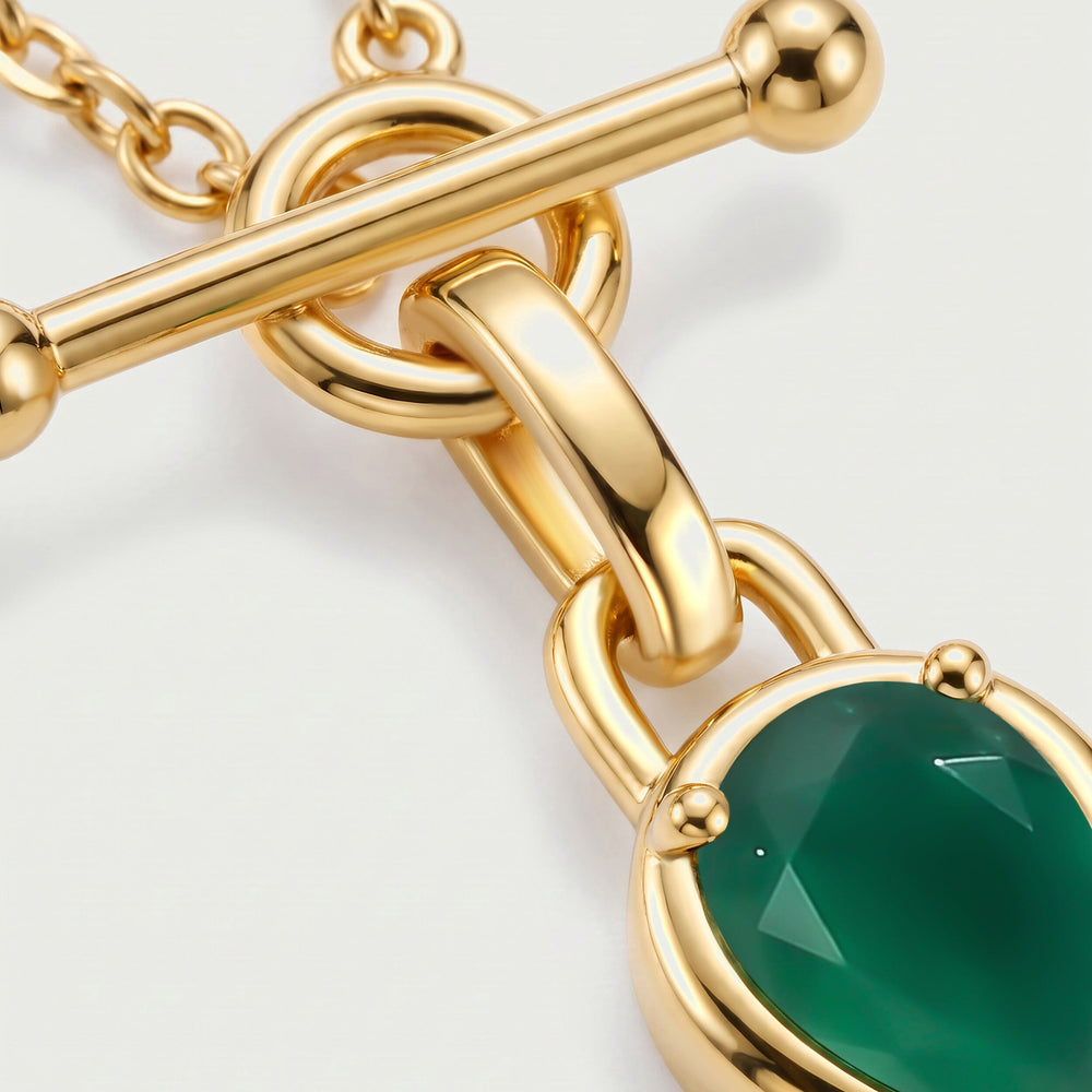 A close view shows the rounded gold-toned clasp ends, connecting bail and facets of the green stone.