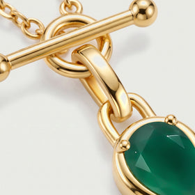A close view shows the rounded gold-toned clasp ends, connecting bail and facets of the green stone.