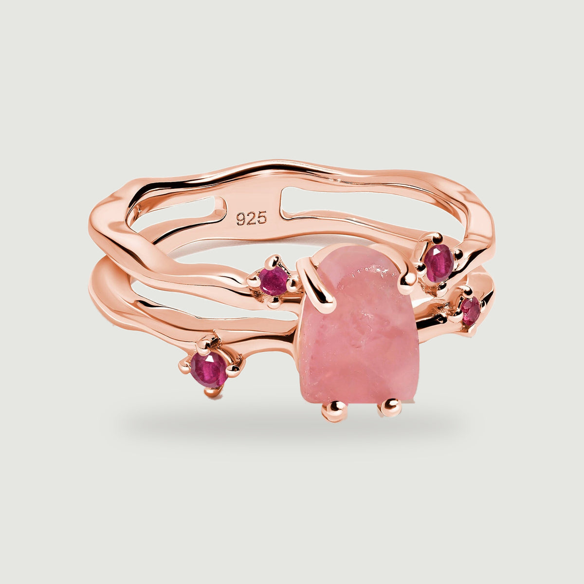 A rose gold vermeil ring with two irregular bands surrounds a pink rose quartz stone and four ruby accents.