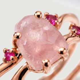 Rose gold vermeil prongs frame a pale pink crystal beside bright ruby accents in a tight detail view.
