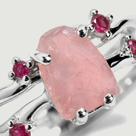 The pink crystal surface and faceted ruby accents are visible between polished sterling silver prongs.