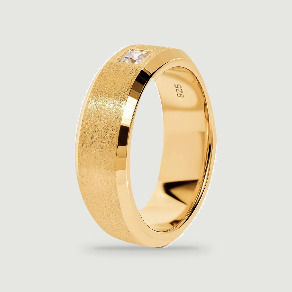 A yellow gold ring stands at an angle with its square stone visible along the upper edge.