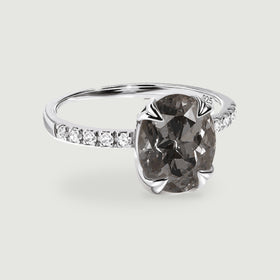 A three-quarter view shows a grey oval gemstone held by silver claws above a slim band with clear shoulder stones.