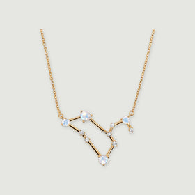 A yellow gold necklace with four pale moonstones and small clear stones rests on a light gray background.